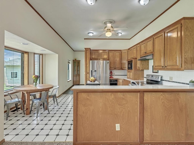 18317 Chestnut Oak Dr, Edmond, OK 73012 - kitchen featuring appliances with stainless steel finishes, light flooring, under cabinet range hood, a peninsula, and tile counters