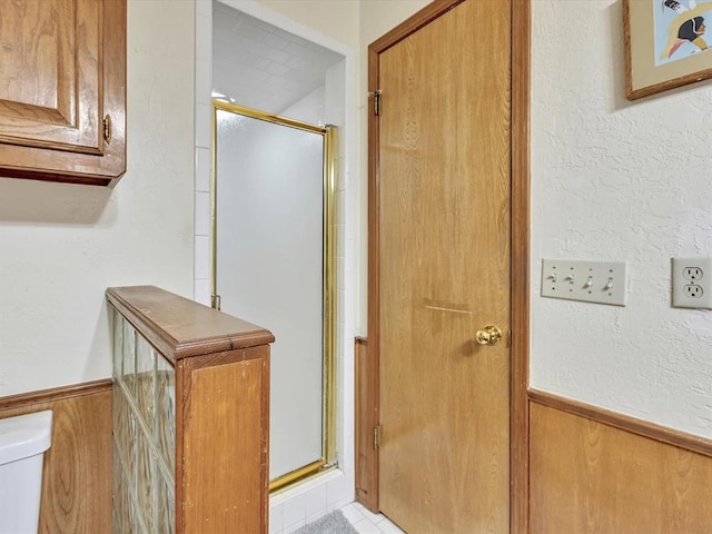 18317 Chestnut Oak Dr, Edmond, OK 73012 - bathroom with a stall shower, wainscoting, wooden walls, and tile patterned flooring