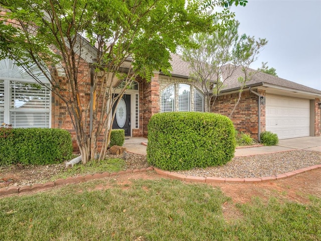 1340 NW 168th St, Edmond, OK 73012 - obstructed view of property featuring brick siding, a shingled roof, an attached garage, and concrete driveway