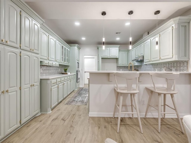 1340 NW 168th St, Edmond, OK 73012 - kitchen featuring a peninsula, decorative backsplash, under cabinet range hood, light wood-style floors, and a breakfast bar