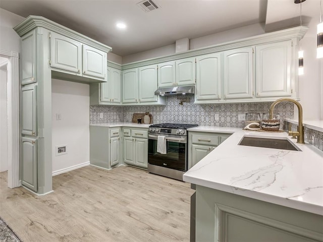 1340 NW 168th St, Edmond, OK 73012 - kitchen with stainless steel gas range, under cabinet range hood, light wood-style floors, decorative backsplash, and pendant lighting