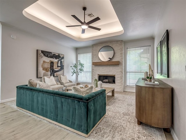 1340 NW 168th St, Edmond, OK 73012 - living room featuring a ceiling fan, a tray ceiling, a fireplace, and wood finished floors