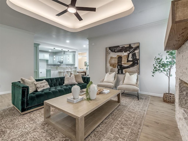 1340 NW 168th St, Edmond, OK 73012 - living area featuring ceiling fan, light wood-type flooring, a tray ceiling, a stone fireplace, and recessed lighting
