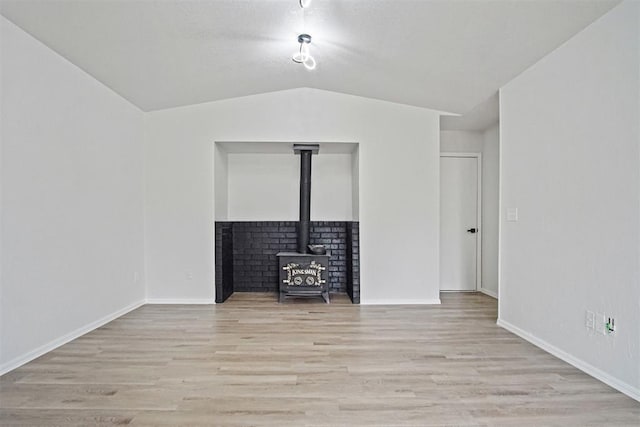 3300 Outpost Cir, Norman, OK 73072 - unfurnished living room featuring a wood stove, light wood finished floors, and vaulted ceiling