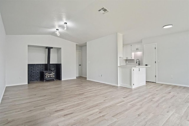 3300 Outpost Cir, Norman, OK 73072 - unfurnished living room featuring a wood stove, light wood-type flooring, and lofted ceiling