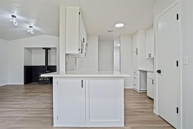 3300 Outpost Cir, Norman, OK 73072 - kitchen featuring a wood stove, white cabinetry, light wood-type flooring, a peninsula, and light countertops