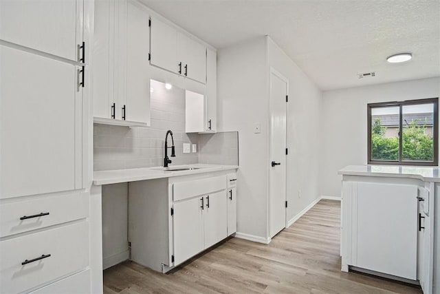3300 Outpost Cir, Norman, OK 73072 - kitchen featuring backsplash, light wood-style floors, light countertops, and white cabinetry