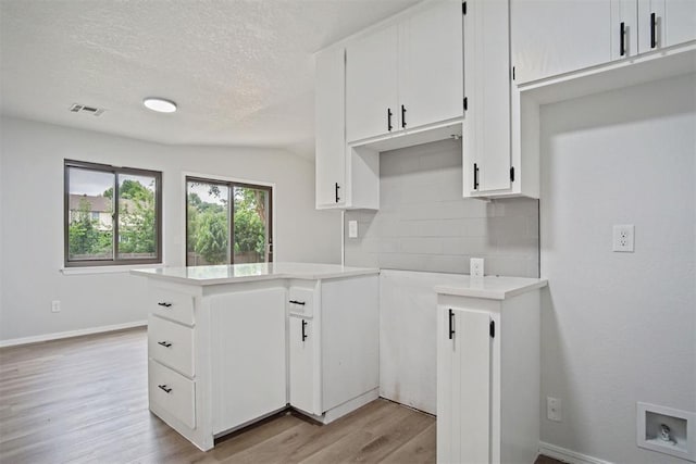 3300 Outpost Cir, Norman, OK 73072 - kitchen with light wood finished floors, light countertops, decorative backsplash, a textured ceiling, and white cabinets