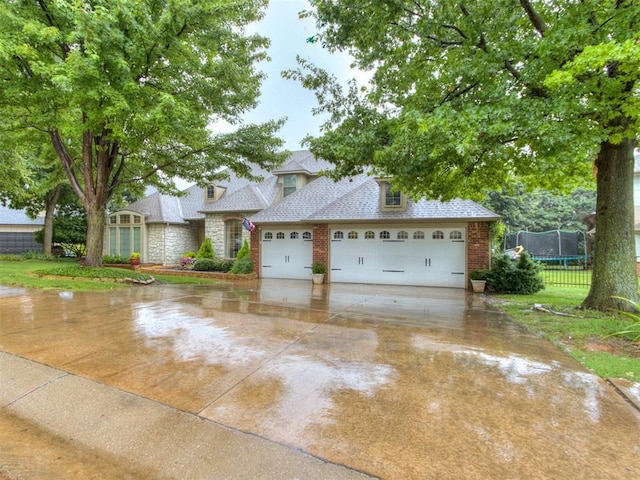 123 E Lakeview Trl, Edmond, OK 73003 - view of front of property with a trampoline, concrete driveway, a shingled roof, a garage, and brick siding