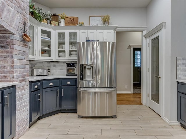 123 E Lakeview Trl, Edmond, OK 73003 - kitchen with stainless steel fridge, white cabinets, light countertops, wood tiled floors, and glass insert cabinets