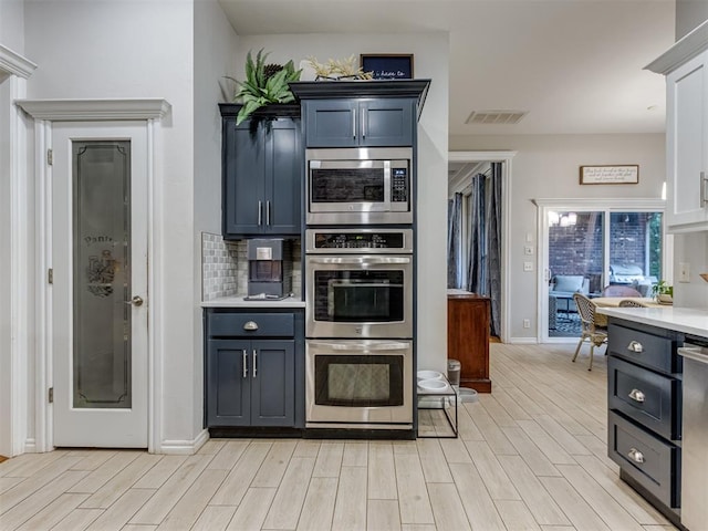 123 E Lakeview Trl, Edmond, OK 73003 - kitchen with stainless steel appliances, light countertops, light wood-style floors, a desk, and decorative backsplash