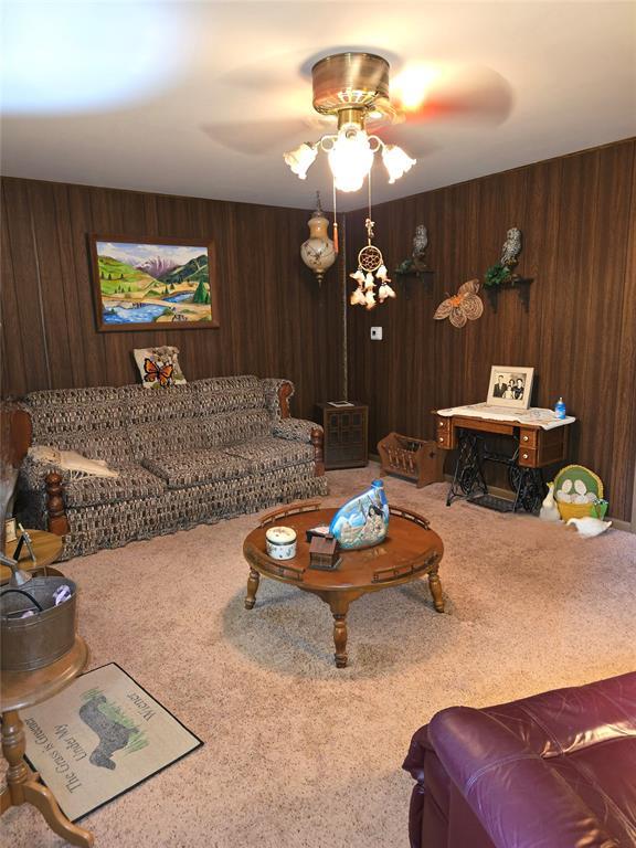 730 N Santa Fe St Unit 4052073333, Pauls Valley, OK 73075 - living room featuring carpet, wooden walls, and ceiling fan