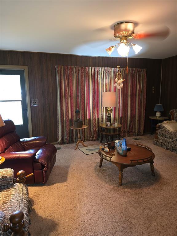 730 N Santa Fe St Unit 4052073333, Pauls Valley, OK 73075 - living room featuring carpet floors, a ceiling fan, and wooden walls