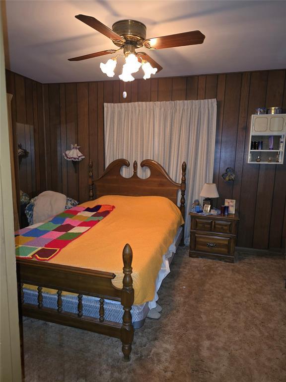 730 N Santa Fe St Unit 4052073333, Pauls Valley, OK 73075 - bedroom with wood walls, carpet flooring, and a ceiling fan