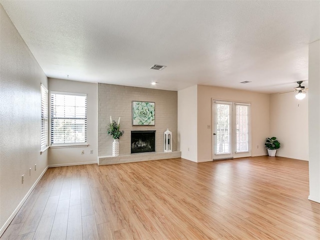 4400 Hemingway Dr Unit 221, Oklahoma City, OK 73118 - unfurnished living room with light wood-type flooring, a brick fireplace, and ceiling fan