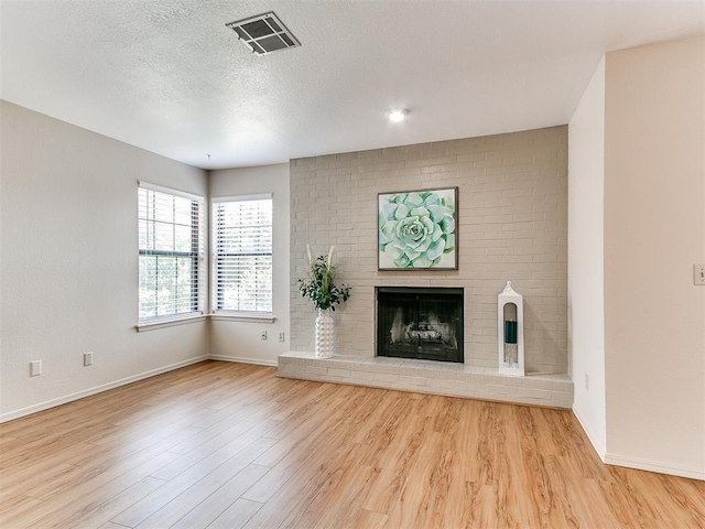 4400 Hemingway Dr Unit 221, Oklahoma City, OK 73118 - unfurnished living room featuring wood finished floors, a fireplace, and a textured ceiling