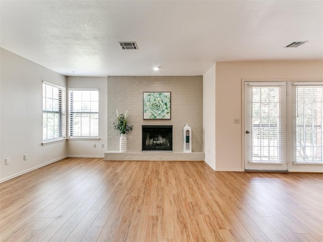 4400 Hemingway Dr Unit 221, Oklahoma City, OK 73118 - unfurnished living room featuring light wood finished floors, a fireplace, and a textured ceiling