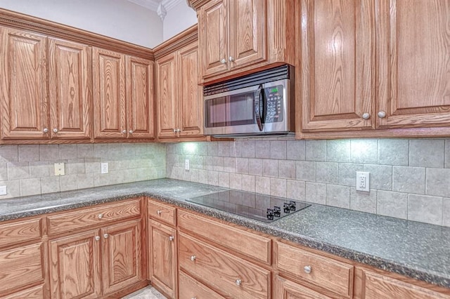 3900 Irvine Dr, Norman, OK 73072 - kitchen featuring stainless steel microwave, black electric stovetop, dark countertops, decorative backsplash, and brown cabinets