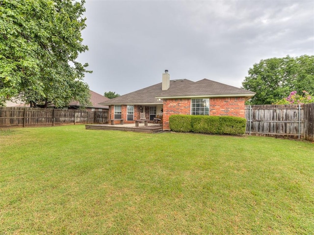 17213 Sunny Hollow Rd, Edmond, OK 73012 - back of property with a fenced backyard, brick siding, a chimney, and a wooden deck