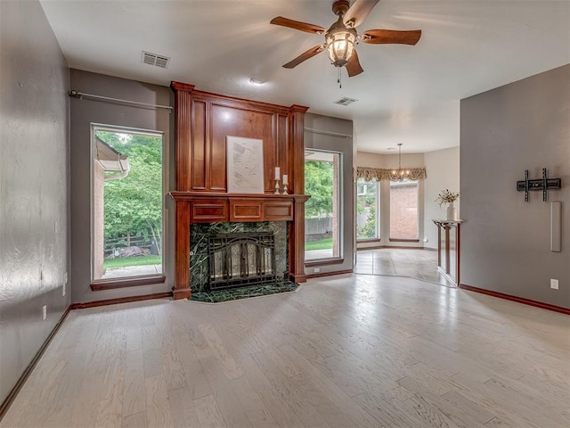3716 Equestrian Ct, Edmond, OK 73034 - unfurnished living room featuring a premium fireplace, light wood-type flooring, a ceiling fan, and plenty of natural light