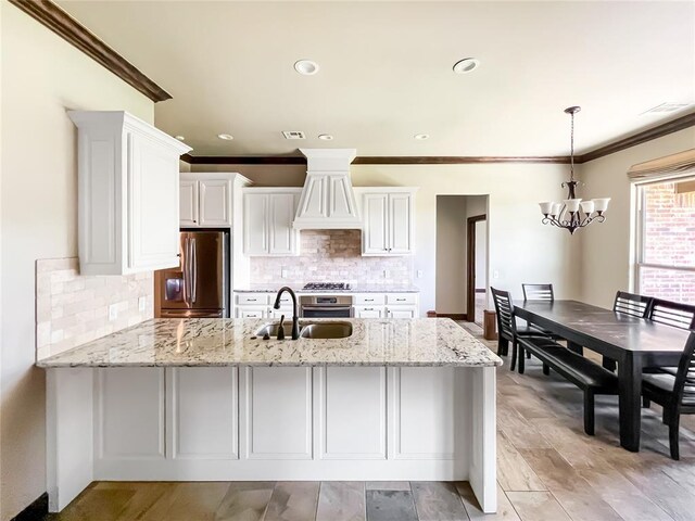 2010 Lakewood, Seminole, OK 74868 - kitchen featuring freestanding refrigerator, ornamental molding, a peninsula, a chandelier, and white cabinetry