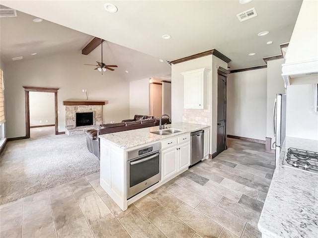 2010 Lakewood, Seminole, OK 74868 - kitchen featuring stainless steel appliances, a stone fireplace, custom range hood, white cabinetry, and ceiling fan