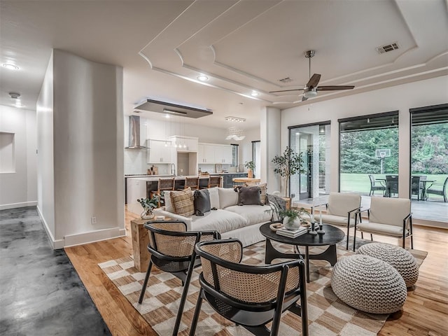 3604 Valley Creek Cir, Edmond, OK 73034 - living area with a tray ceiling, a ceiling fan, and light wood-style floors