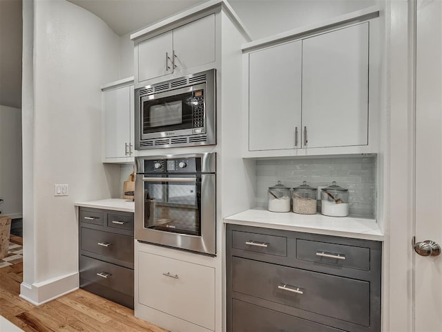 3604 Valley Creek Cir, Edmond, OK 73034 - kitchen featuring stainless steel appliances, light wood finished floors, tasteful backsplash, light countertops, and white cabinetry