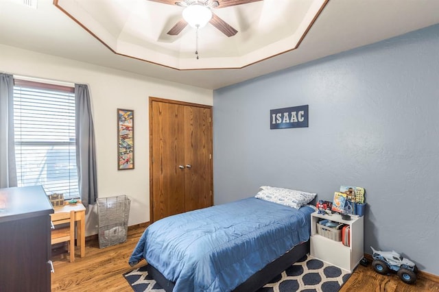 2525 Steeplechase Rd, Edmond, OK 73034 - bedroom with wood finished floors, a raised ceiling, a closet, and ceiling fan