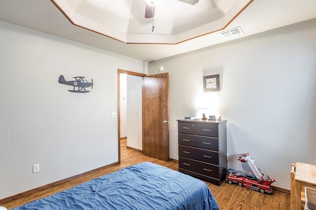 2525 Steeplechase Rd, Edmond, OK 73034 - bedroom with light wood-style flooring, a tray ceiling, and a ceiling fan