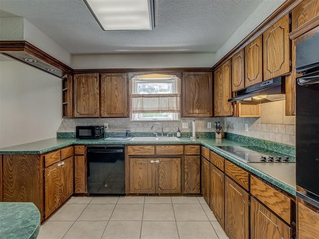 3213 Creekwood Ct, Norman, OK 73072 - kitchen with black appliances, under cabinet range hood, decorative backsplash, brown cabinets, and a textured ceiling