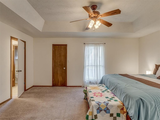 3213 Creekwood Ct, Norman, OK 73072 - bedroom with a tray ceiling, light carpet, a textured ceiling, ensuite bathroom, and a ceiling fan