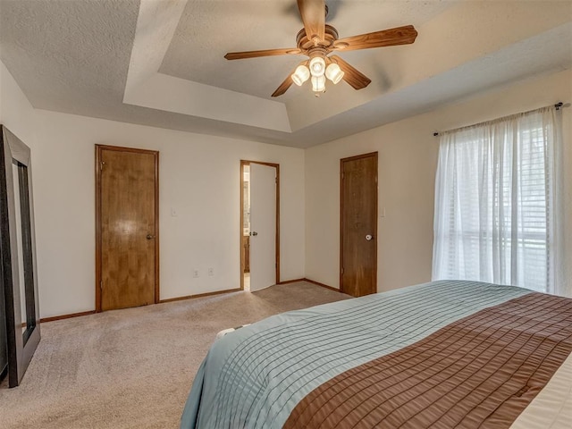3213 Creekwood Ct, Norman, OK 73072 - bedroom featuring a tray ceiling, light carpet, a textured ceiling, and ceiling fan