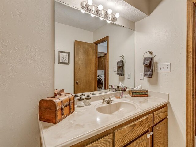 3213 Creekwood Ct, Norman, OK 73072 - bathroom featuring washer / dryer, vanity, and a textured wall