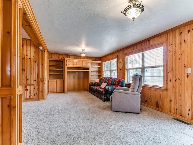 1016 Maple Ave, Yukon, OK 73099 - living room with wooden walls, a textured ceiling, light colored carpet, built in shelves, and ornamental molding