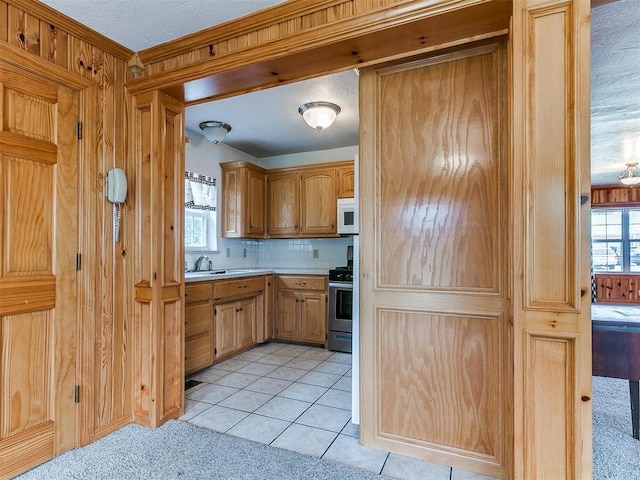 1016 Maple Ave, Yukon, OK 73099 - kitchen featuring white microwave, stainless steel range, light countertops, backsplash, and light tile patterned floors