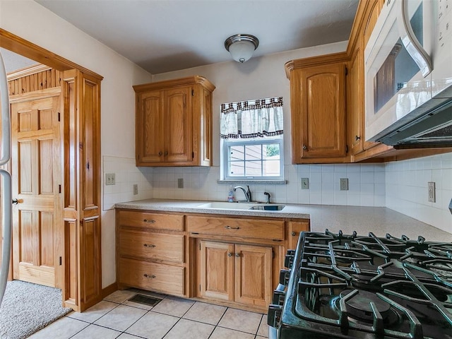 1016 Maple Ave, Yukon, OK 73099 - kitchen featuring white microwave, range with gas cooktop, light countertops, brown cabinetry, and light tile patterned floors