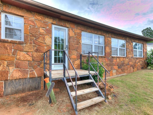 1016 Maple Ave, Yukon, OK 73099 - exterior entry at dusk featuring stone siding, a deck, and a yard
