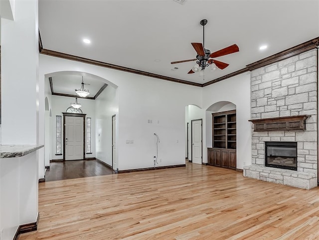 18501 El Greco Dr, Edmond, OK 73012 - unfurnished living room featuring ornamental molding, ceiling fan, light wood-type flooring, and a stone fireplace