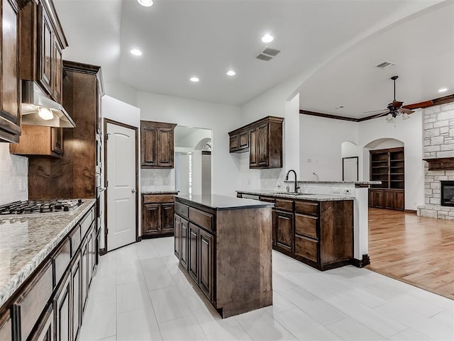 18501 El Greco Dr, Edmond, OK 73012 - kitchen with arched walkways, stainless steel gas cooktop, ceiling fan, tasteful backsplash, and recessed lighting