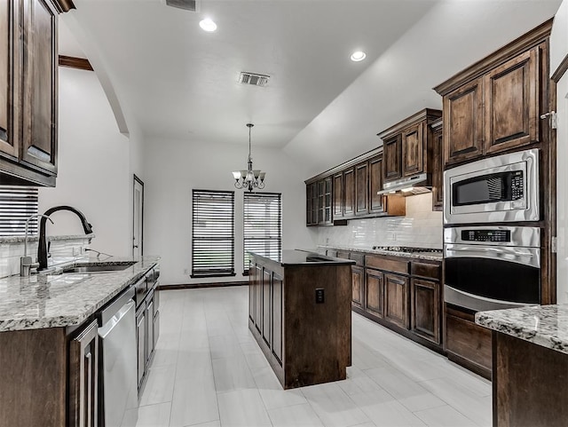 18501 El Greco Dr, Edmond, OK 73012 - kitchen featuring appliances with stainless steel finishes, dark brown cabinetry, decorative backsplash, a center island, and lofted ceiling