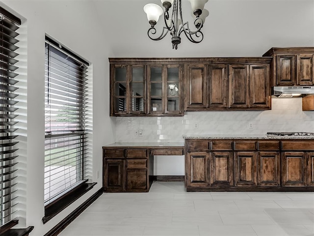 18501 El Greco Dr, Edmond, OK 73012 - kitchen with under cabinet range hood, dark brown cabinetry, stainless steel gas stovetop, and decorative backsplash