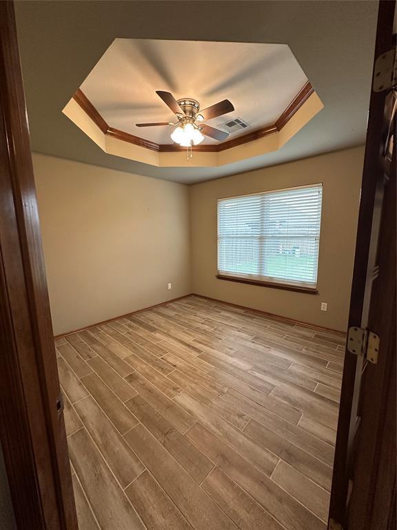 712 N Cherokee Way, Mustang, OK 73064 - spare room with a tray ceiling, wood finished floors, a ceiling fan, and crown molding