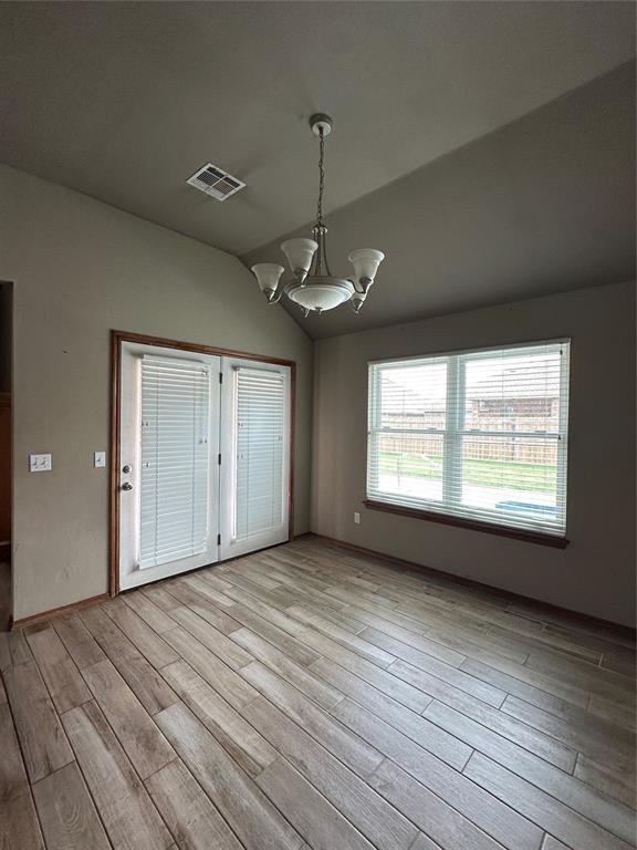 712 N Cherokee Way, Mustang, OK 73064 - unfurnished dining area featuring a chandelier, light wood-style floors, and vaulted ceiling