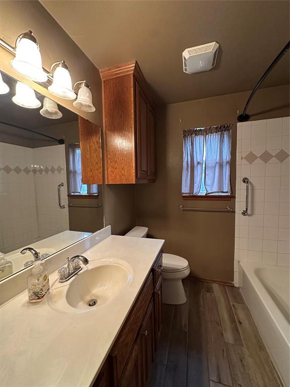 712 N Cherokee Way, Mustang, OK 73064 - bathroom with wood finished floors, vanity, and shower / washtub combination