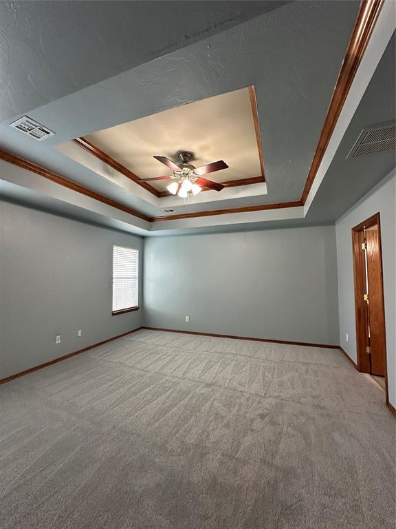 712 N Cherokee Way, Mustang, OK 73064 - unfurnished room featuring a tray ceiling, carpet floors, ceiling fan, and crown molding