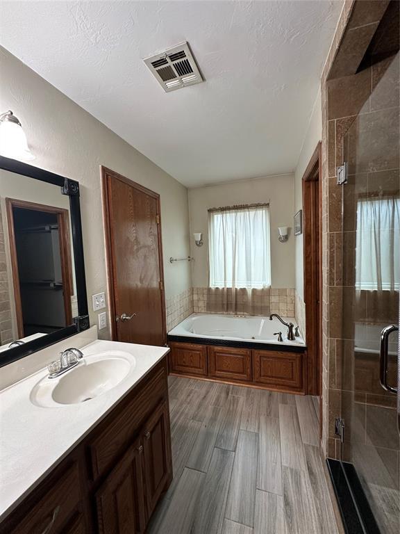 712 N Cherokee Way, Mustang, OK 73064 - bathroom featuring a bath, vanity, and a shower stall