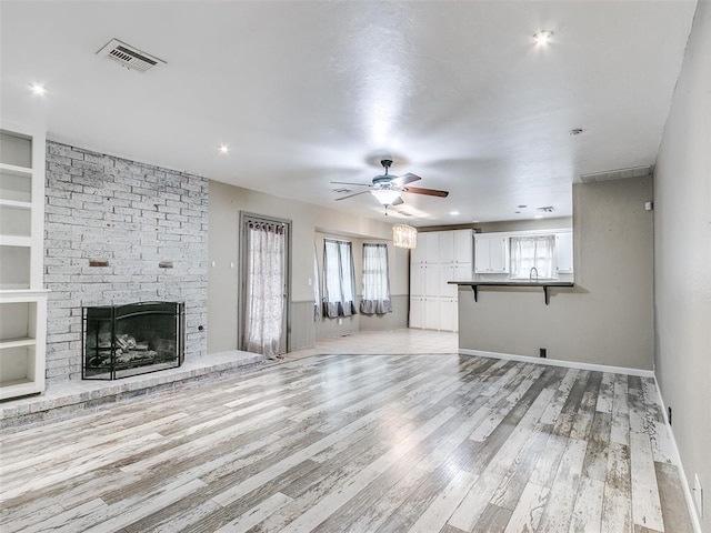 1040 Mabel C Fry Blvd, Yukon, OK 73099 - unfurnished living room featuring ceiling fan, light wood finished floors, a fireplace, and built in shelves