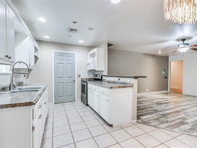 1040 Mabel C Fry Blvd, Yukon, OK 73099 - kitchen with electric range, white microwave, a peninsula, light tile patterned floors, and decorative backsplash