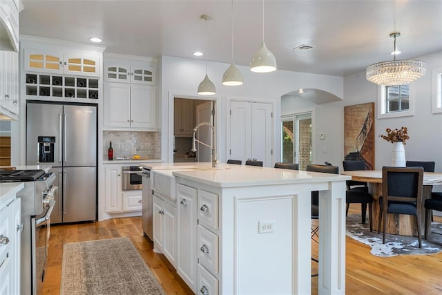 1517 Station St, Edmond, OK 73034 - kitchen with high end appliances, a breakfast bar area, arched walkways, light wood finished floors, and recessed lighting